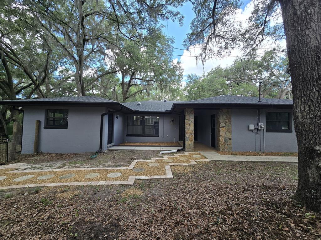 A gray single-story house with a stone pillar, dark trim, and a gravel walkway — 3512 SW SHOREWOOD DRIVE, DUNNELLON, FL