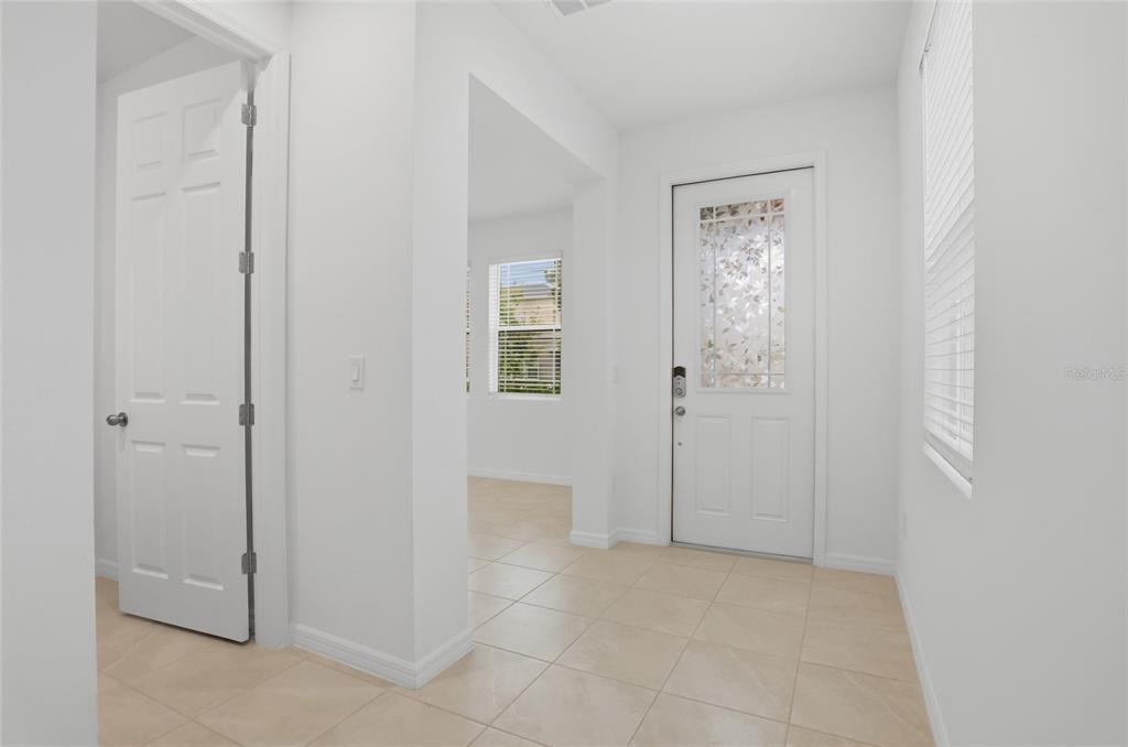 A bright entryway features light tile flooring, white walls, a front door, and an interior door — 16396 PRAIRIE SCHOOL DRIVE, WINTER GARDEN, FL