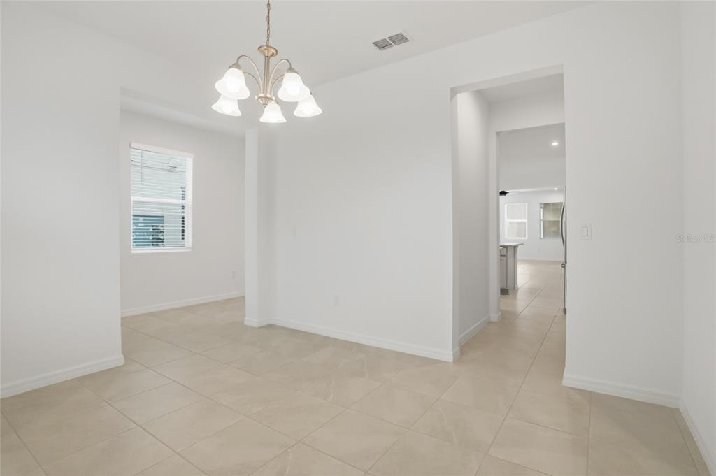 A bright dining area with a chandelier, tile flooring, and an open doorway to the kitchen — 16396 PRAIRIE SCHOOL DRIVE, WINTER GARDEN, FL