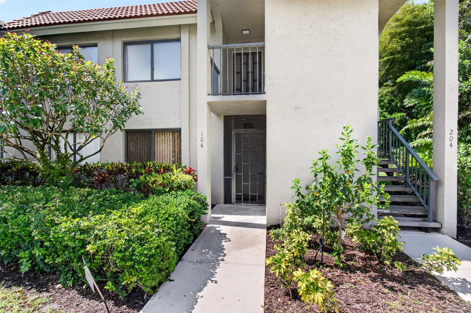 The exterior of a two-story residential building features a ground-floor entrance and outdoor stairs — 5561 Fairway Park Drive # 104, Boynton Beach FL 33437, BOYNTON BEACH, FL