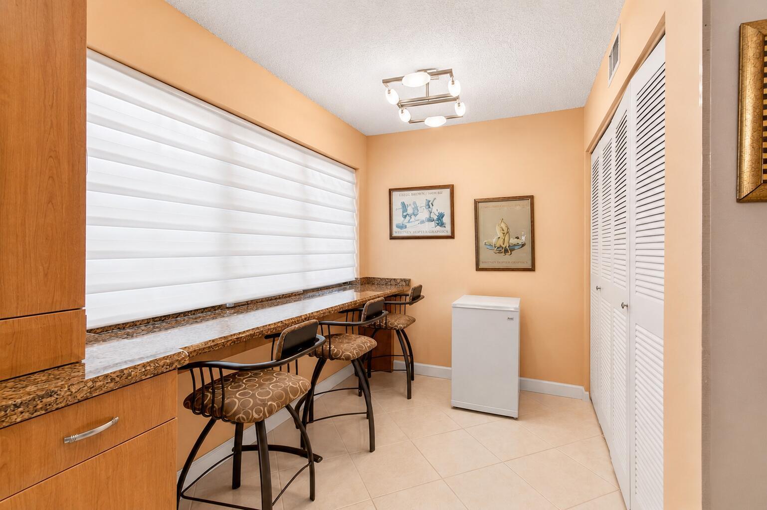 A small room features a long granite countertop with bar stools and a white mini-fridge — 5561 Fairway Park Drive # 104, Boynton Beach FL 33437, BOYNTON BEACH, FL