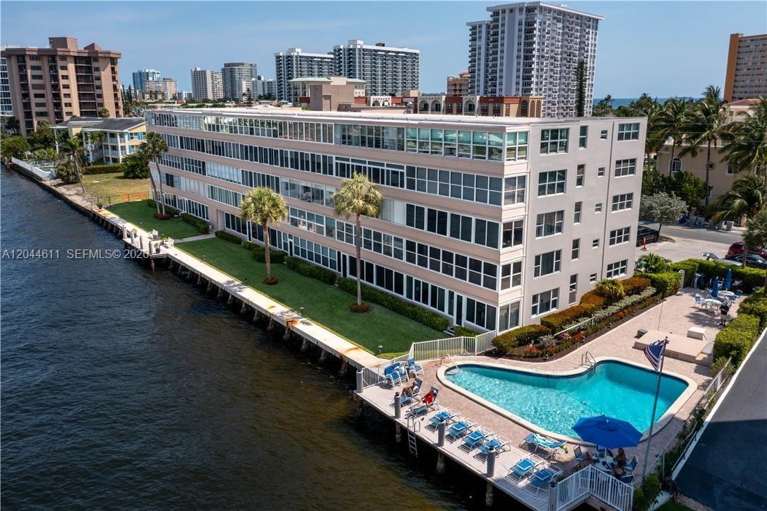 An aerial view shows a multi-story apartment building situated along a canal near the ocean — 401 N Riverside Dr # 504, Pompano Beach FL 33062, POMPANO BEACH, FL
