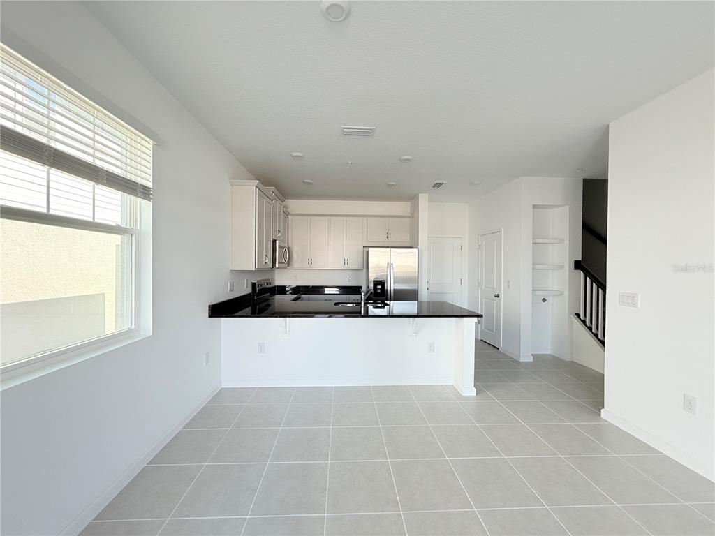 A kitchen features white cabinets, black countertops, stainless steel appliances, and light-colored tile flooring — 4124 SADLER ROAD, APOPKA, FL