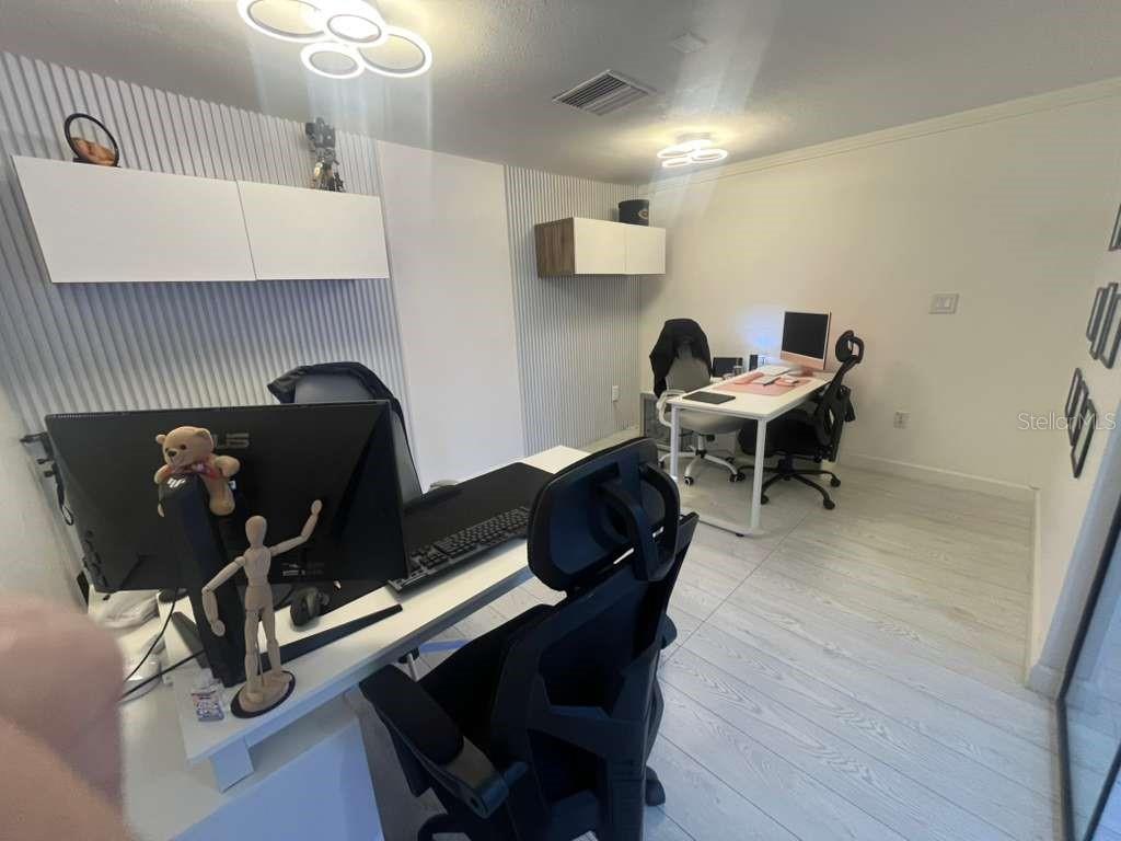 A home office features two desks, white wood-look flooring, and slatted wall paneling — 11601 S ORANGE BLOSSOM TRAIL UNIT 201, ORLANDO, FL