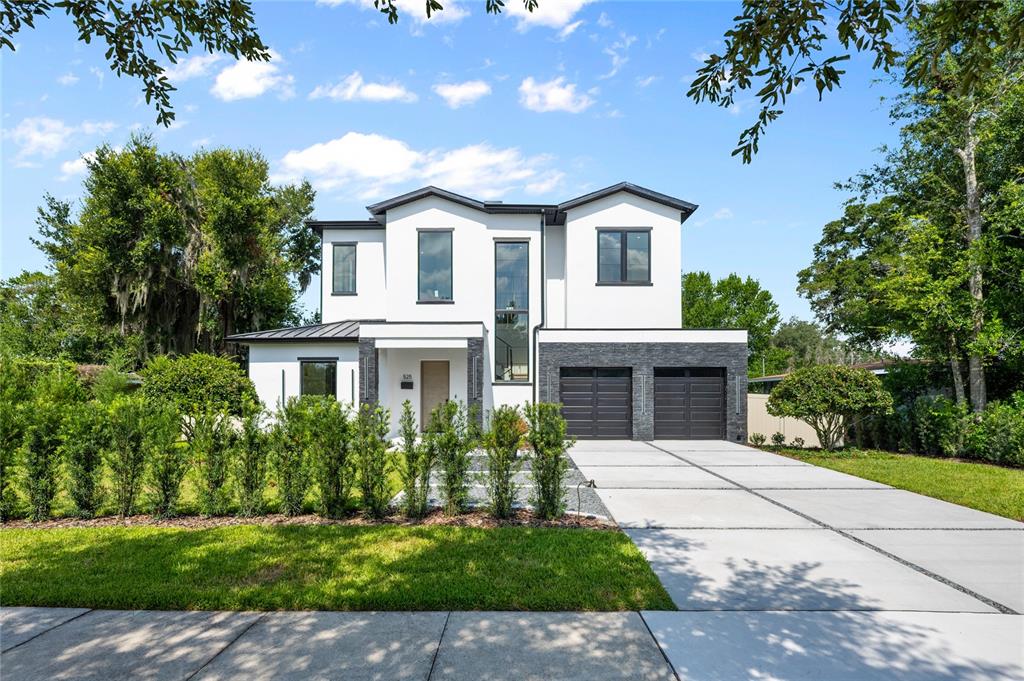 A two-story modern house with a white facade, dark stone accents, and a concrete driveway — 525 S LAKEMONT AVENUE, WINTER PARK, FL