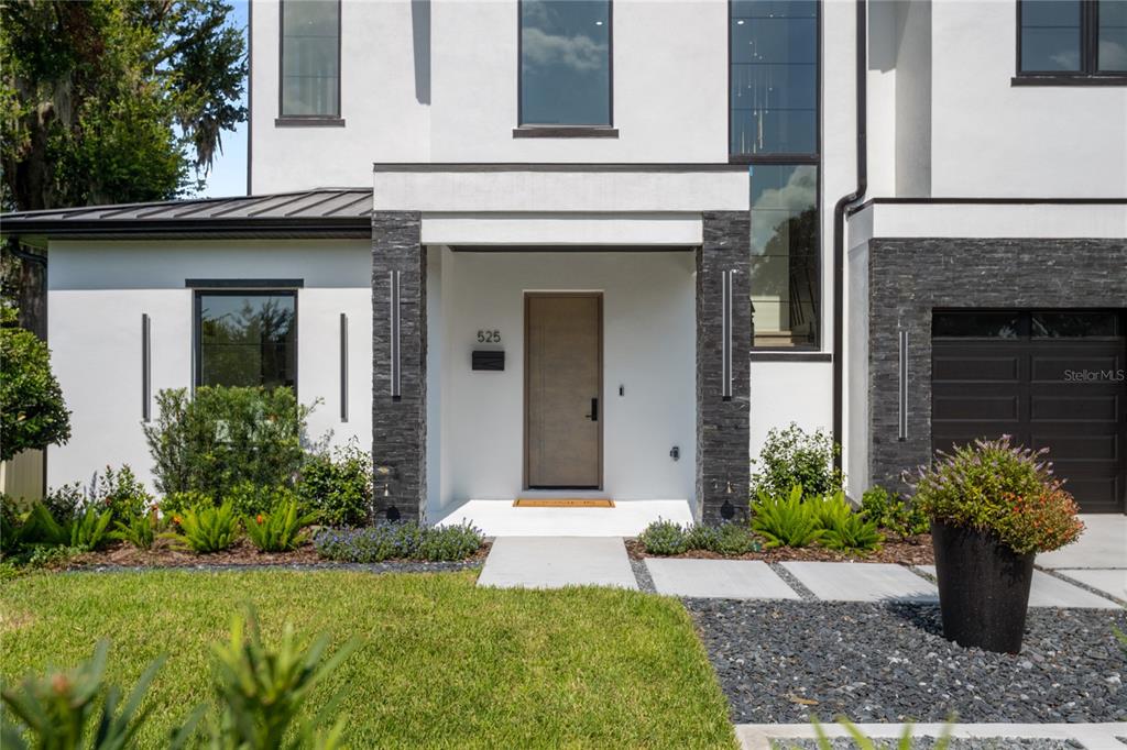 A modern two-story home features a white stucco exterior, dark stone accents, and a front door — 525 S LAKEMONT AVENUE, WINTER PARK, FL