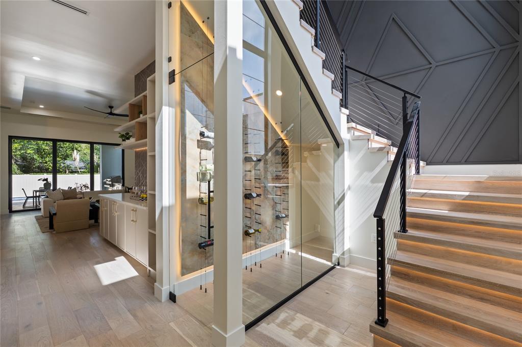 A glass-enclosed wine display is built under a staircase with light wood steps and railings — 525 S LAKEMONT AVENUE, WINTER PARK, FL