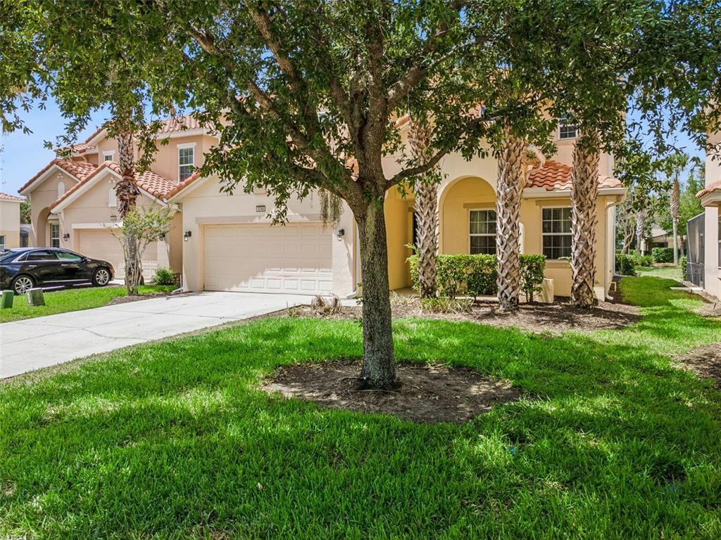 A two-story suburban house with a tan stucco exterior, tile roof, and a two-car garage — 4348 ACORN COURT, DAVENPORT, FL