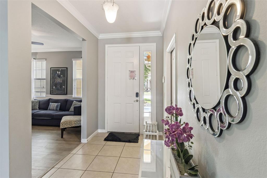 A tiled entryway features a white front door, a decorative mirror, and a living room — 4348 ACORN COURT, DAVENPORT, FL