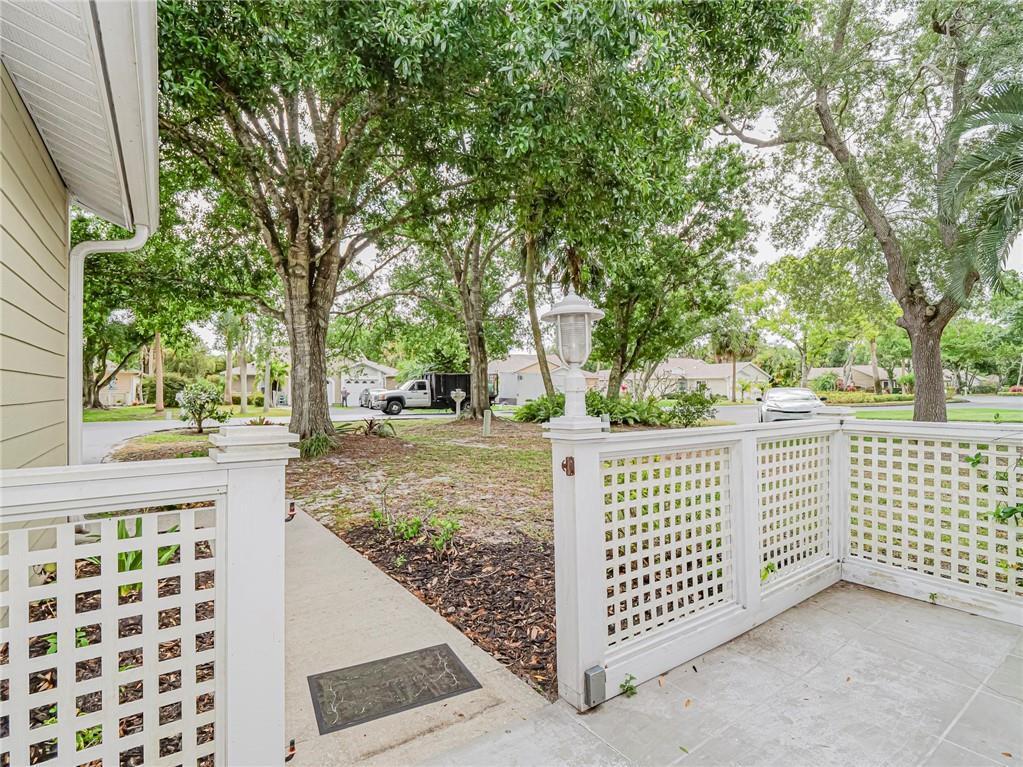 A white lattice fence encloses a paved patio area with a view of the yard — 1875 Sixty Oaks Lane, Vero Beach FL 32966, VERO BEACH, FL