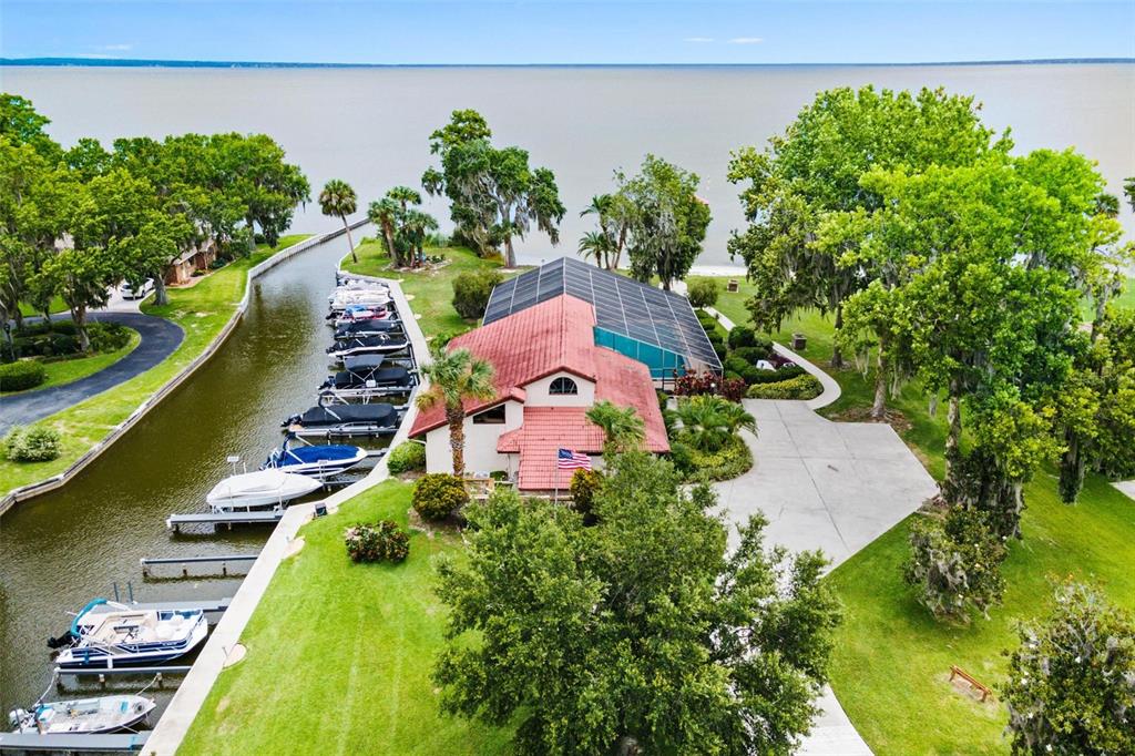 An aerial view shows a house with a red roof and pool cage beside a canal — 402 CLUSTERWOOD DRIVE, YALAHA, FL