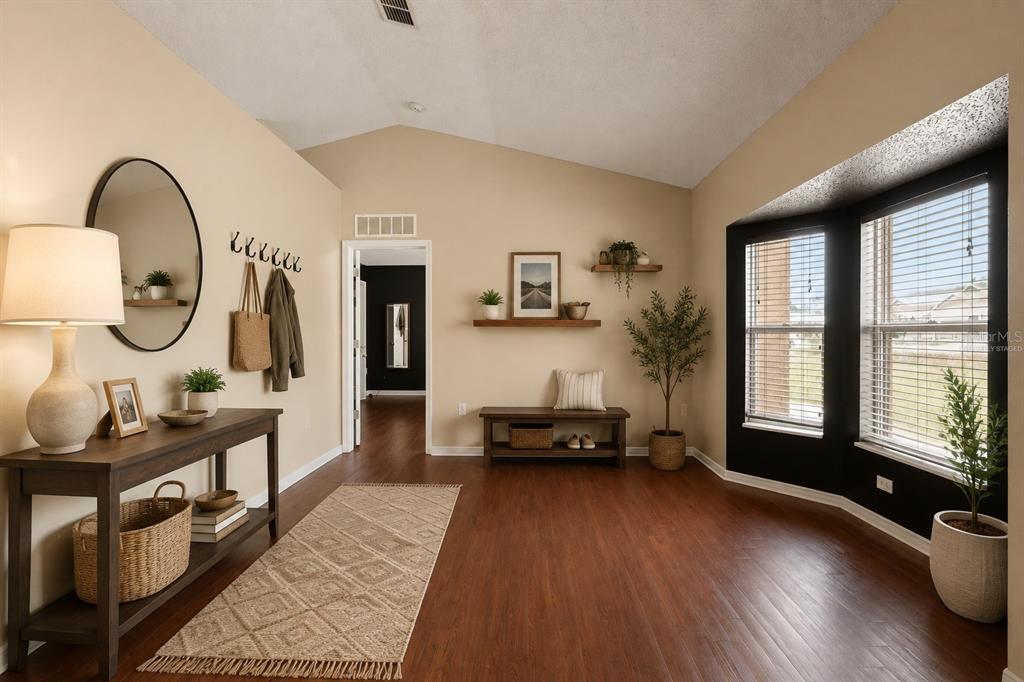An entryway features a console table, a bench, wall shelves, and dark wood flooring — 4416 DIOR ROAD, SPRING HILL, FL