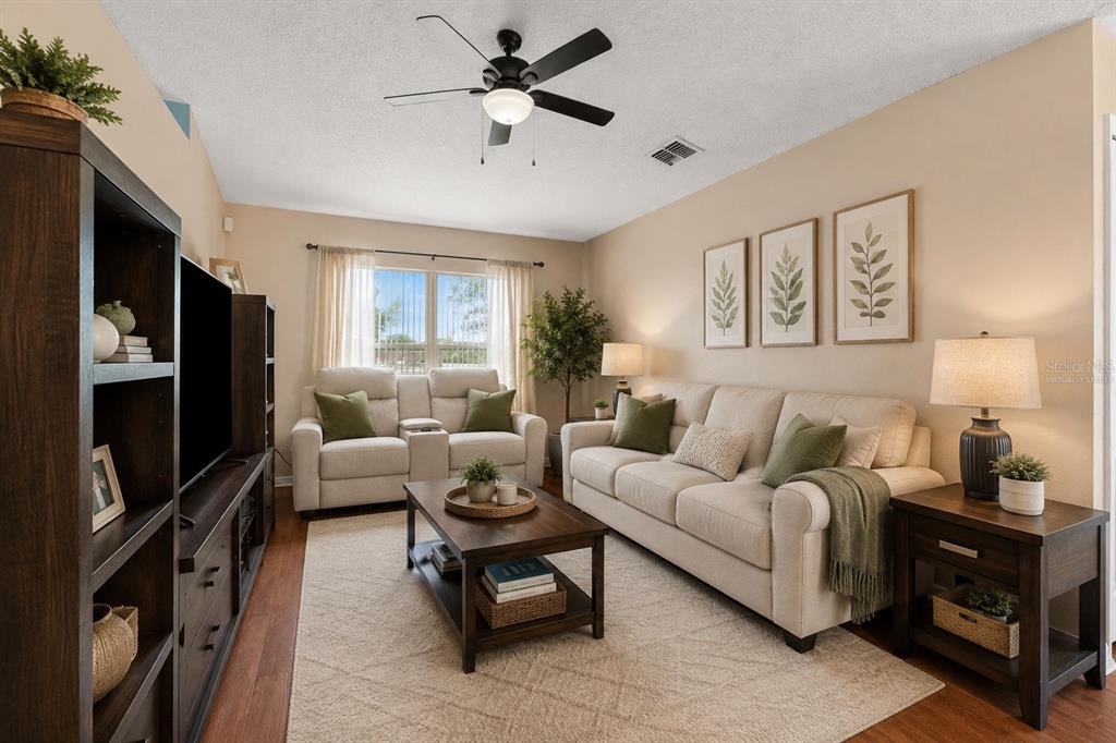 A living room features a beige sofa, a loveseat, a coffee table, and dark wood furniture — 4416 DIOR ROAD, SPRING HILL, FL