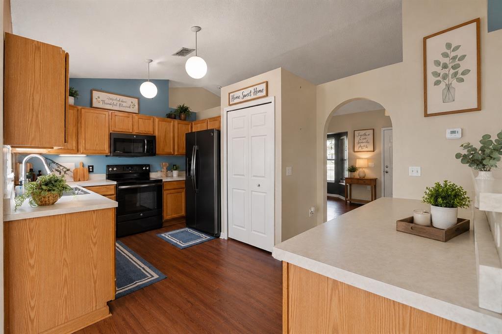 A kitchen with oak cabinets, black appliances, and a white arched doorway leading to another room — 4416 DIOR ROAD, SPRING HILL, FL