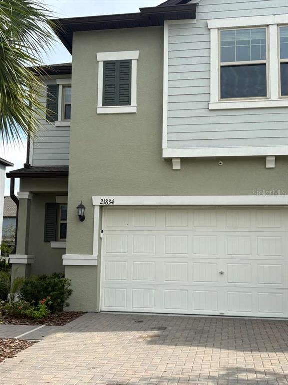 The exterior of a two-story house features a garage, light-colored siding, and a paved driveway — 21834 ADRIATIC LANE, LAND O LAKES, FL