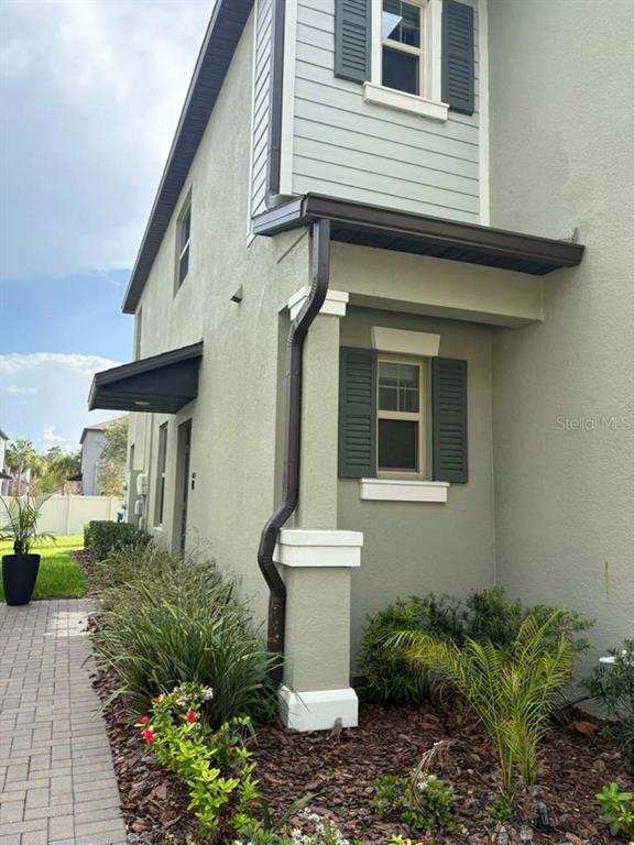 The exterior of a two-story house features light green stucco, dark shutters, and a downspout — 21834 ADRIATIC LANE, LAND O LAKES, FL