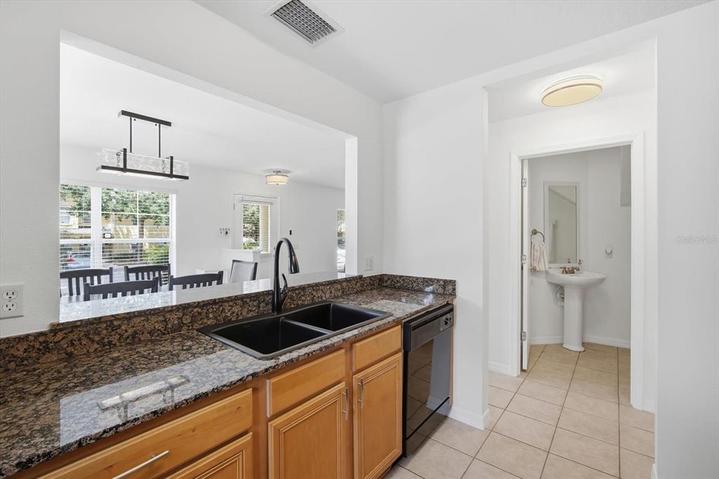 A kitchen with granite countertops, a black double sink, and a view into a bathroom — 3435 CASTLE STONE COURT, VALRICO, FL