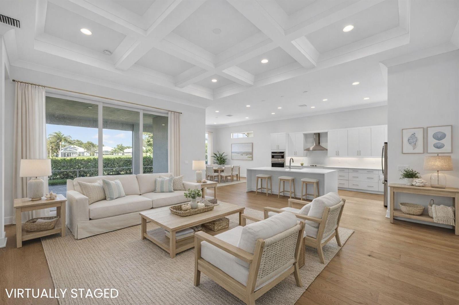 A bright, open-concept living room and kitchen featuring a coffered ceiling and hardwood floors — VERO BEACH, FL