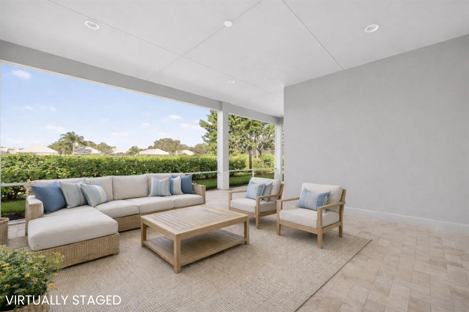 A virtually staged covered patio features a sectional sofa, two armchairs, and a coffee table — VERO BEACH, FL