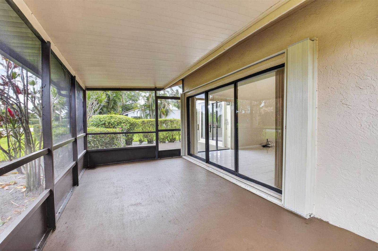 A screened-in patio with a concrete floor and sliding glass doors leading into a home — 5580 Piping Rock Drive, Boynton Beach FL 33437, BOYNTON BEACH, FL