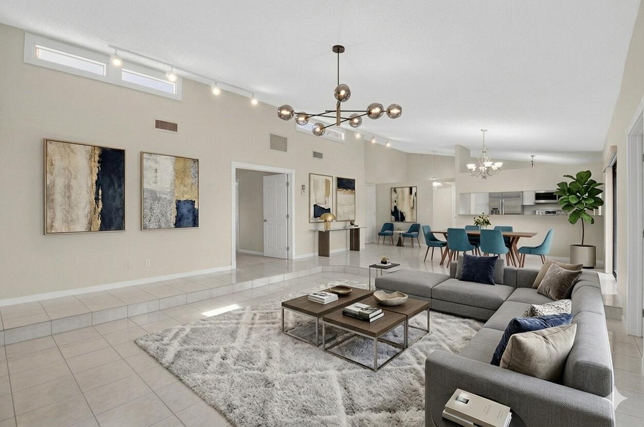 A sunken living room with gray sectional seating, tile flooring, and an open-concept dining area — 5580 Piping Rock Drive, Boynton Beach FL 33437, BOYNTON BEACH, FL