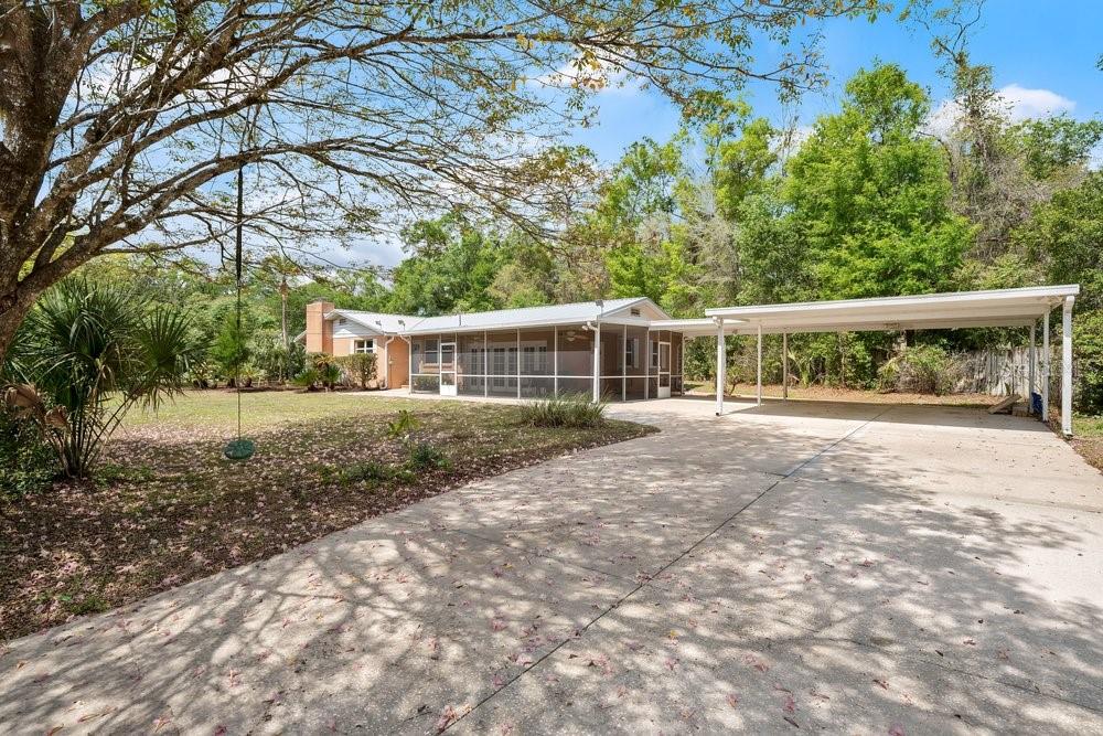 A single-story house with a screened-in porch and a detached carport sits on a lawn — 5137 MOUNT PLYMOUTH ROAD, APOPKA, FL