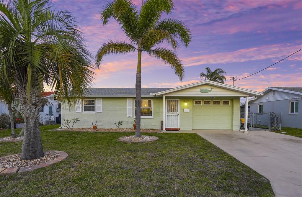 A single-story light green house with a palm tree in the front yard at sunset — 12532 5TH ISLE, HUDSON, FL