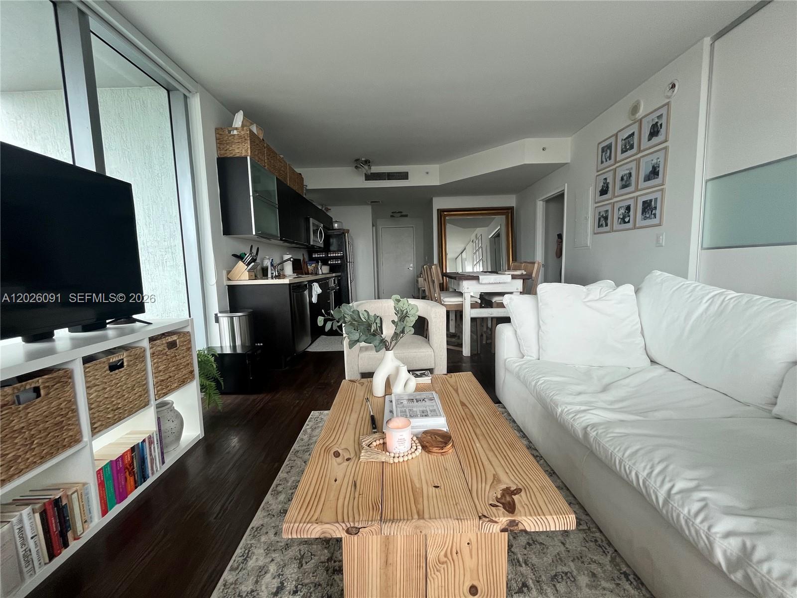 A living room with a white sofa, wooden coffee table, and an adjacent open kitchen — 90 SW 3rd St # 1705, Miami FL 33130, MIAMI, FL