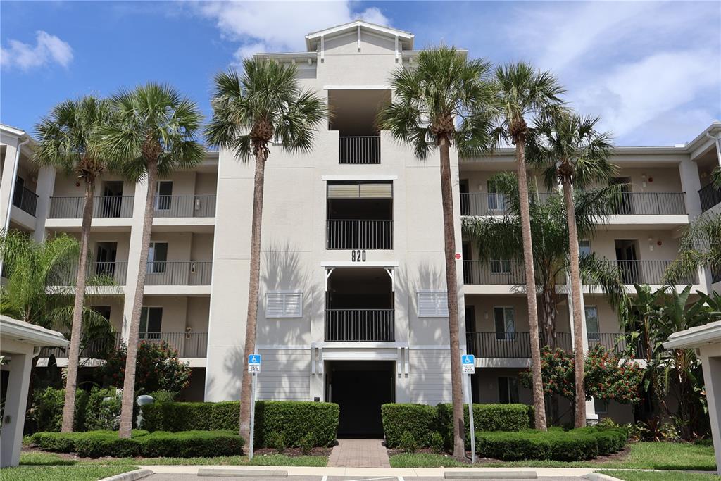 A multi-story apartment building exterior with palm trees and a central entrance labeled 820 — 920 TIDEWATER SHORES LOOP UNIT 301, BRADENTON, FL