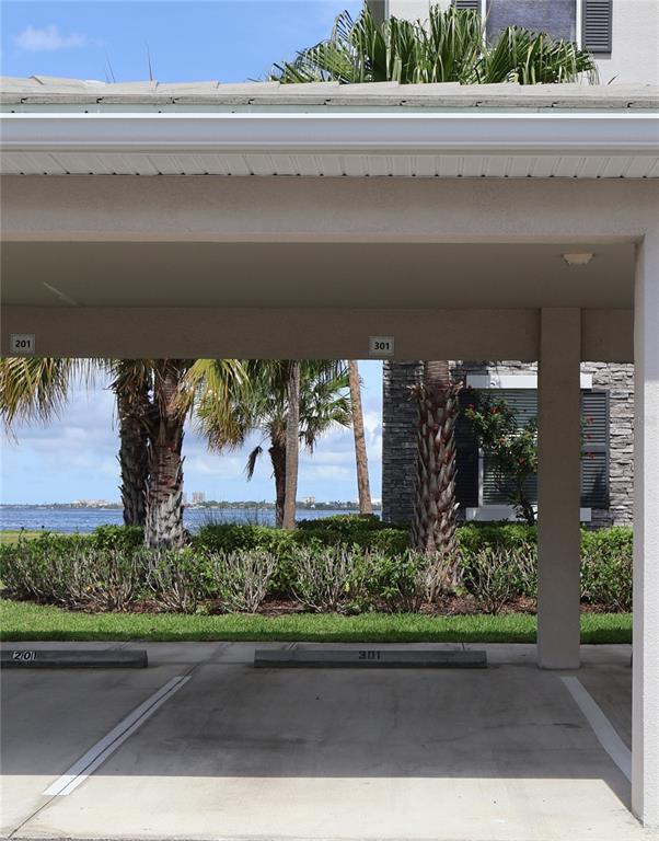 A covered parking area features two numbered spaces with a view of palm trees and water — 920 TIDEWATER SHORES LOOP UNIT 301, BRADENTON, FL