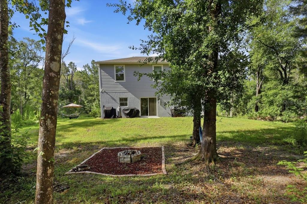 A two-story house with gray siding sits on a grassy lot with a fire pit — 4856 STEPHENS STREET, HASTINGS, FL