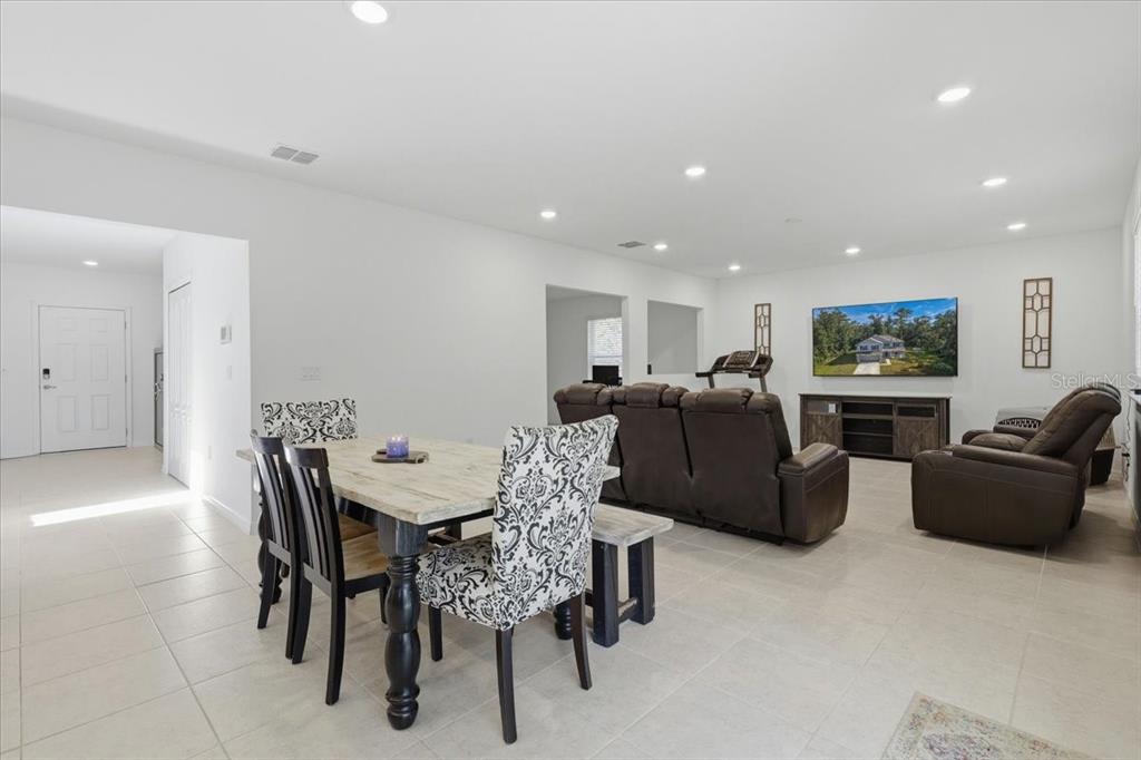 A dining area with a patterned chair sits in front of a living room with recliners — 4856 STEPHENS STREET, HASTINGS, FL