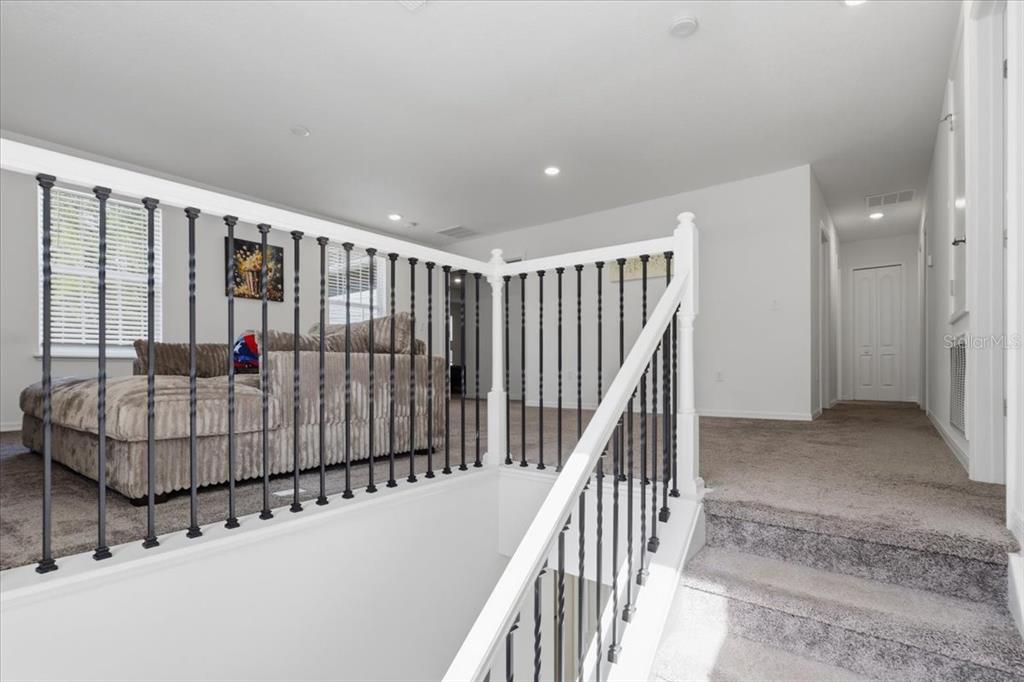 A carpeted landing features a staircase with white railings and black metal balusters — 4856 STEPHENS STREET, HASTINGS, FL