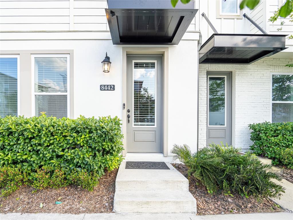 The exterior of a modern townhouse features a gray front door and a concrete step — 8442 SPERRY STREET, ORLANDO, FL