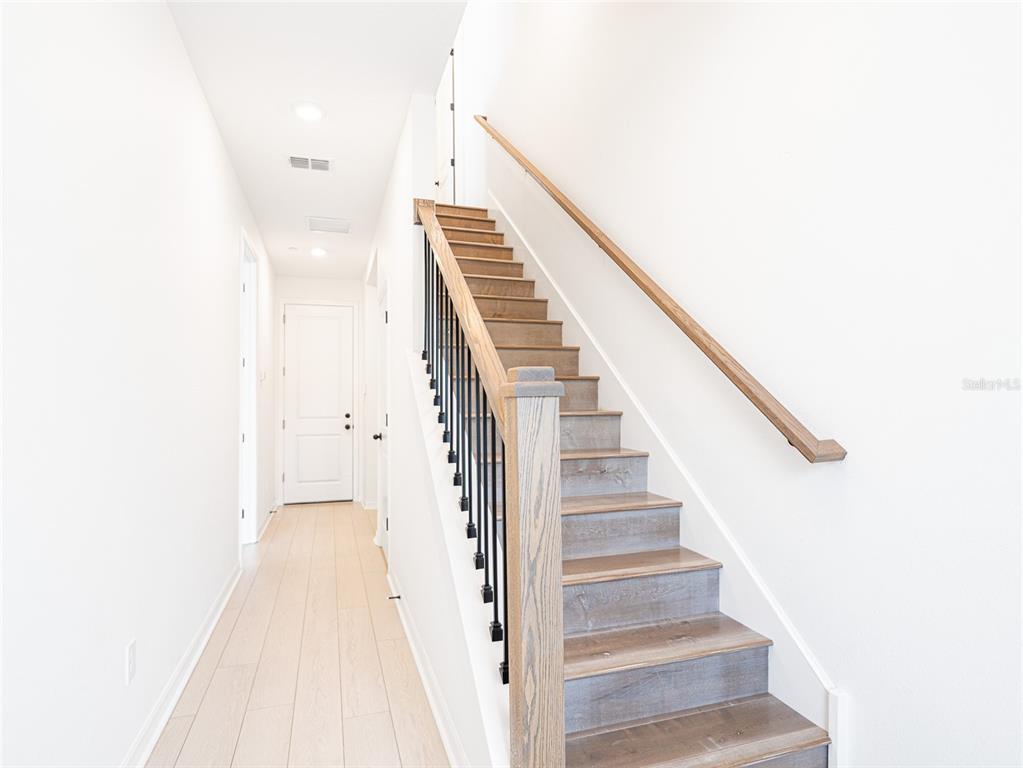 A hallway features light wood flooring, white walls, and a staircase with wooden treads — 8442 SPERRY STREET, ORLANDO, FL
