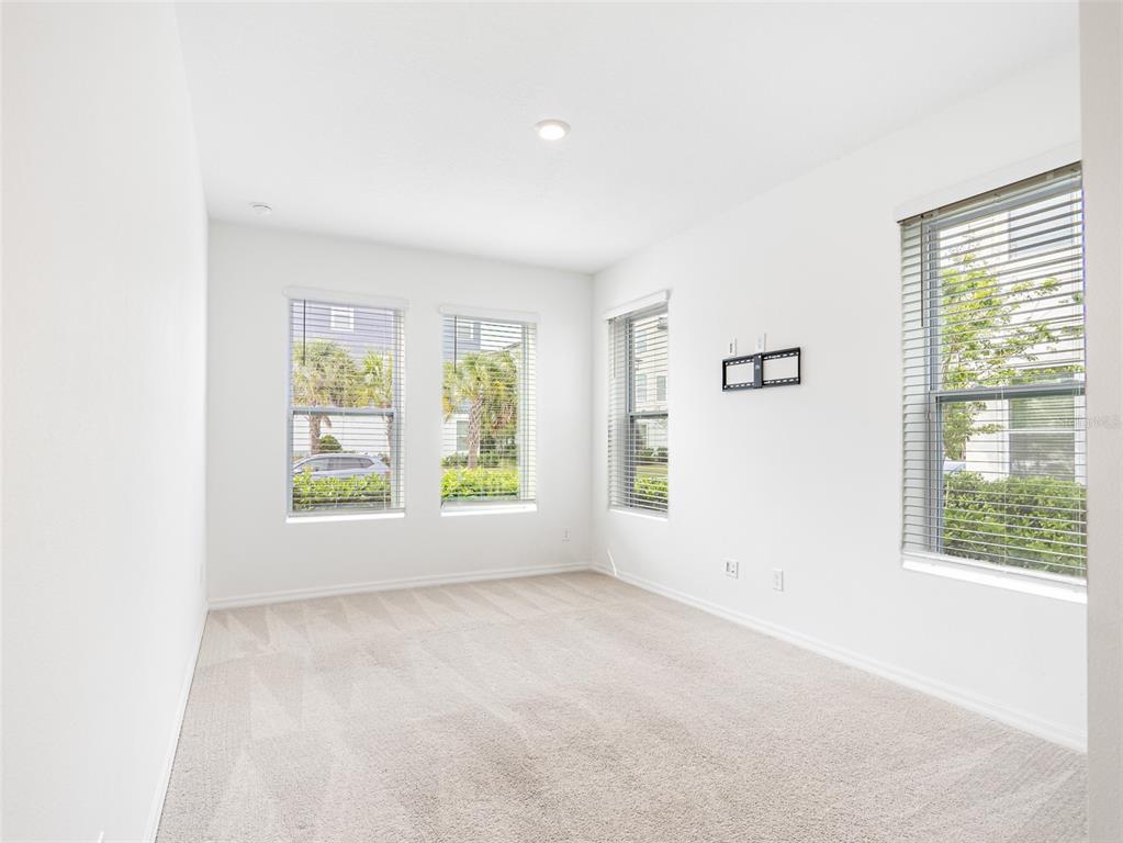 An empty room features white walls, beige carpeting, and four windows with horizontal blinds — 8442 SPERRY STREET, ORLANDO, FL
