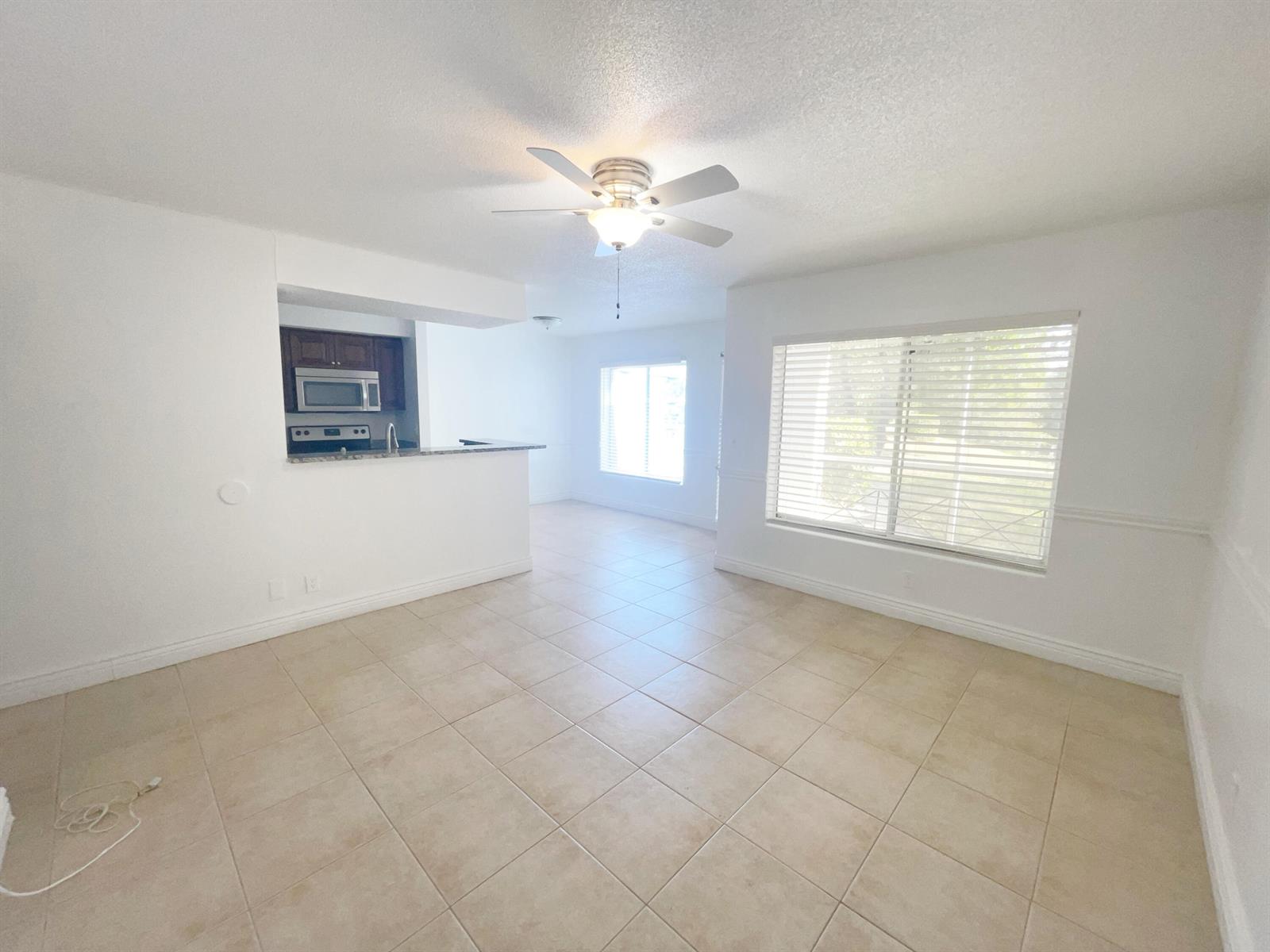 An open-concept living and dining area features white walls, tile flooring, and a ceiling fan — 815 W Boynton Beach Boulevard # 102, Boynton Beach FL 33426, BOYNTON BEACH, FL