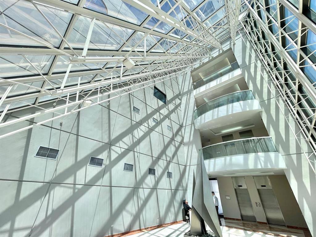A modern atrium features a glass ceiling, multi-level balconies, and a large metal sculpture — 1 CALLE 1, GUAYNABO, PR