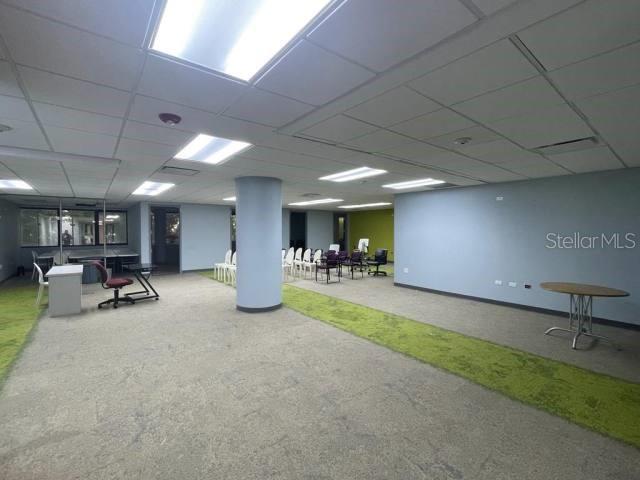 An open office space features a central support column, drop ceiling, and carpeted flooring — 1 CALLE 1, GUAYNABO, PR