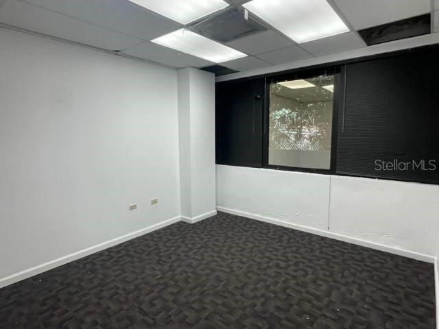An empty office space features white walls, dark patterned carpeting, and a large window — 1 CALLE 1, GUAYNABO, PR