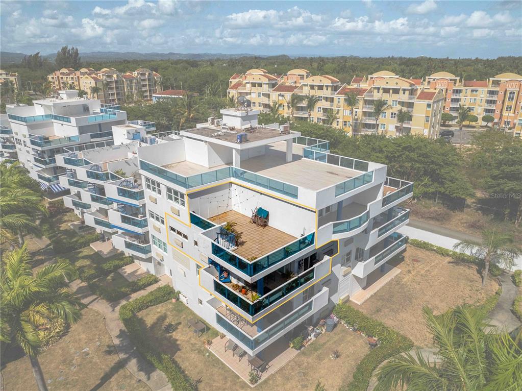 An aerial view of a multi-story apartment building with highlighted balconies and a rooftop terrace — 1 CALLE EL CHARLIE UNIT CO-308, LOIZA, PR