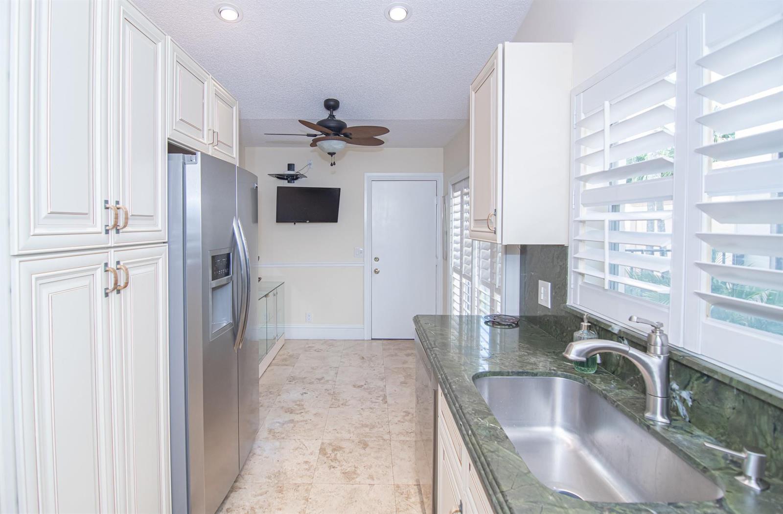A kitchen with stainless steel appliances, green stone countertops, and light-colored cabinetry — 8410 Brussels Way, Boca Raton FL 33434, BOCA RATON, FL