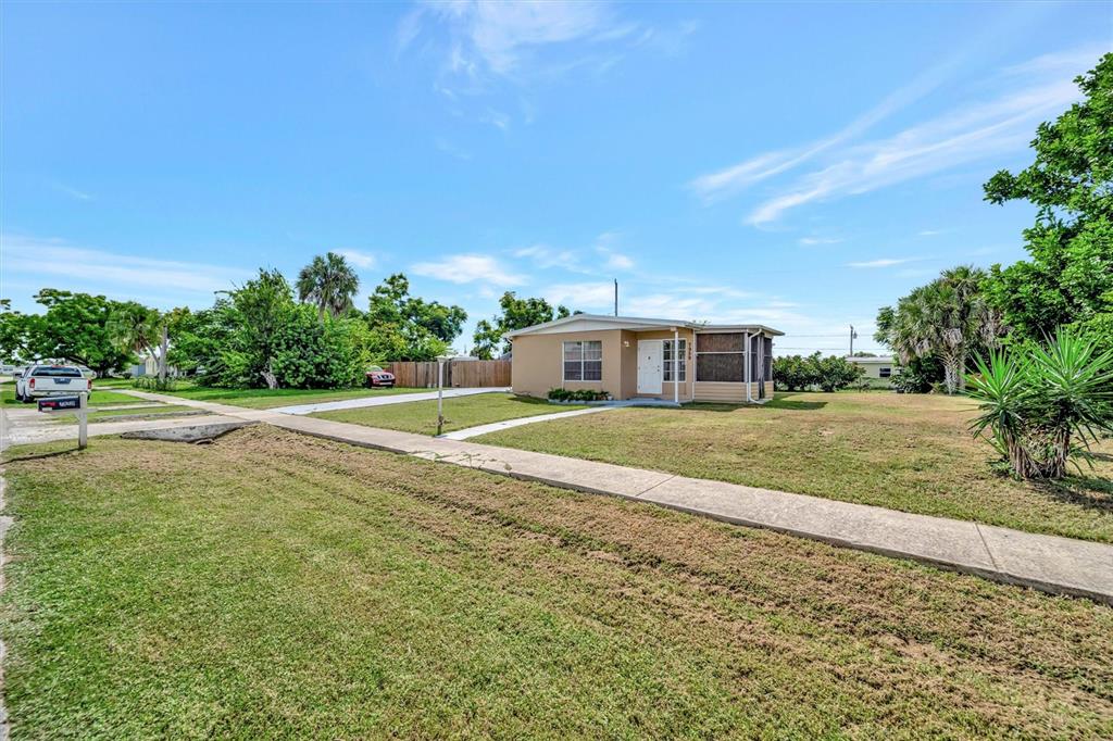 A single-story house with a screened porch sits on a grassy lot under a blue sky — 7959 HYDE PARK AVENUE, NORTH PORT, FL