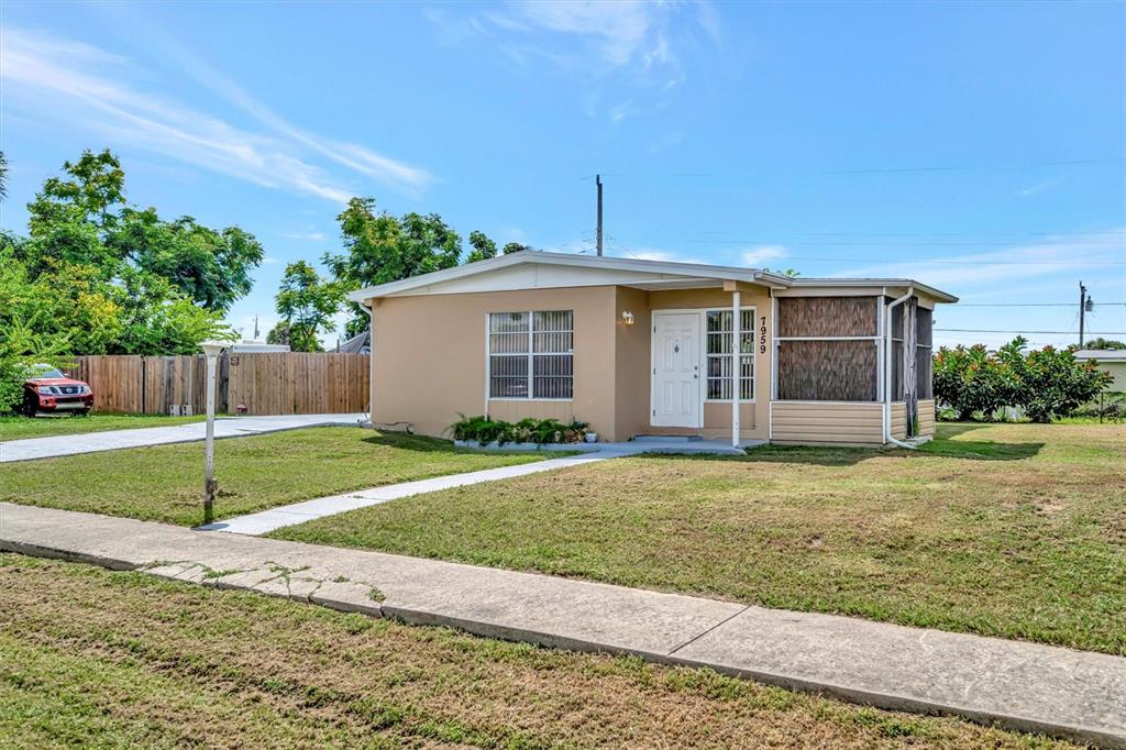A single-story tan house with a white front door and a screened-in porch — 7959 HYDE PARK AVENUE, NORTH PORT, FL