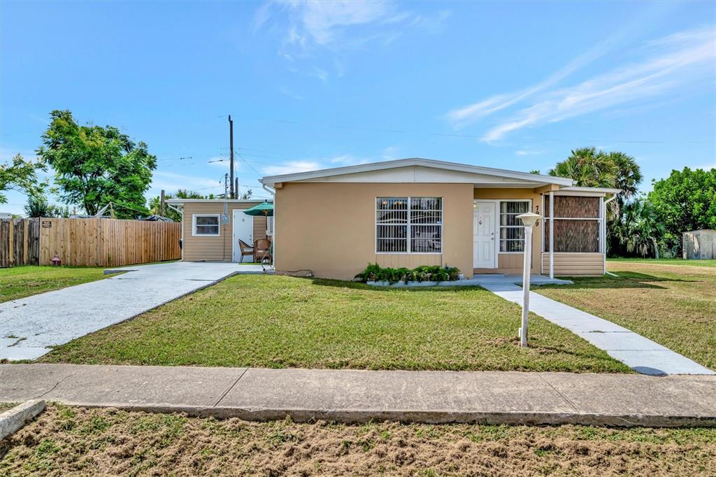 A single-story tan house with a white door, large window, and a concrete driveway — 7959 HYDE PARK AVENUE, NORTH PORT, FL