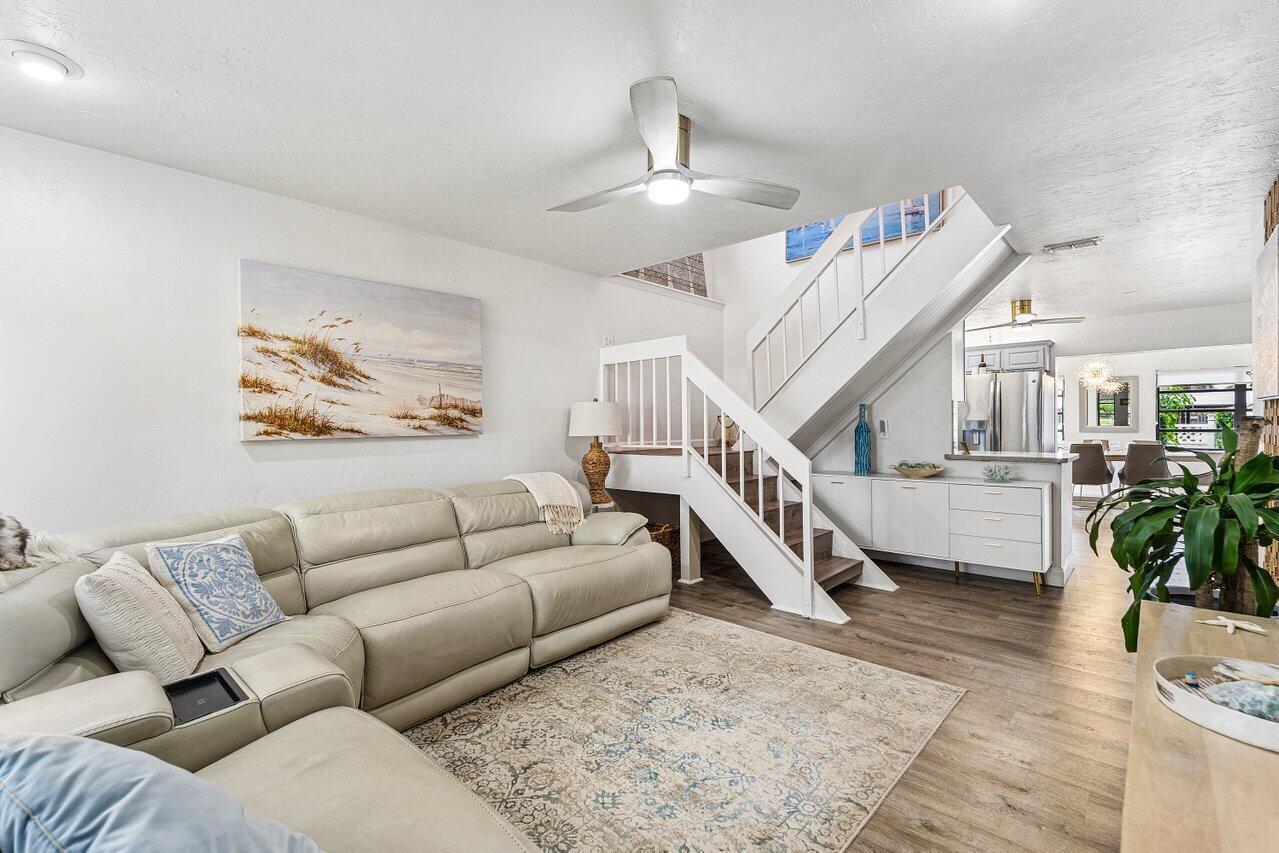 A living room features a beige sectional sofa, a staircase, and light wood flooring — 2101 N Palm Circle, North Palm Beach FL 33408, NORTH PALM BEACH, FL