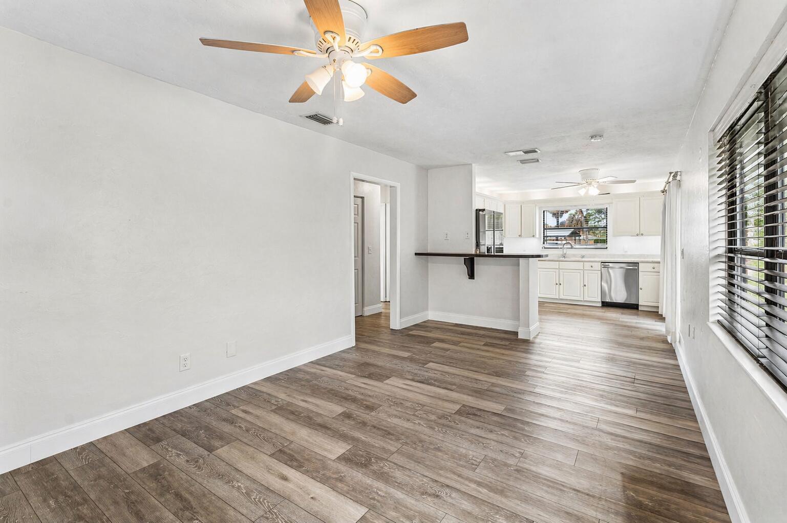 A bright dining area with wood-look flooring opens into a kitchen with white cabinets — 2101 N Palm Circle, North Palm Beach FL 33408, NORTH PALM BEACH, FL