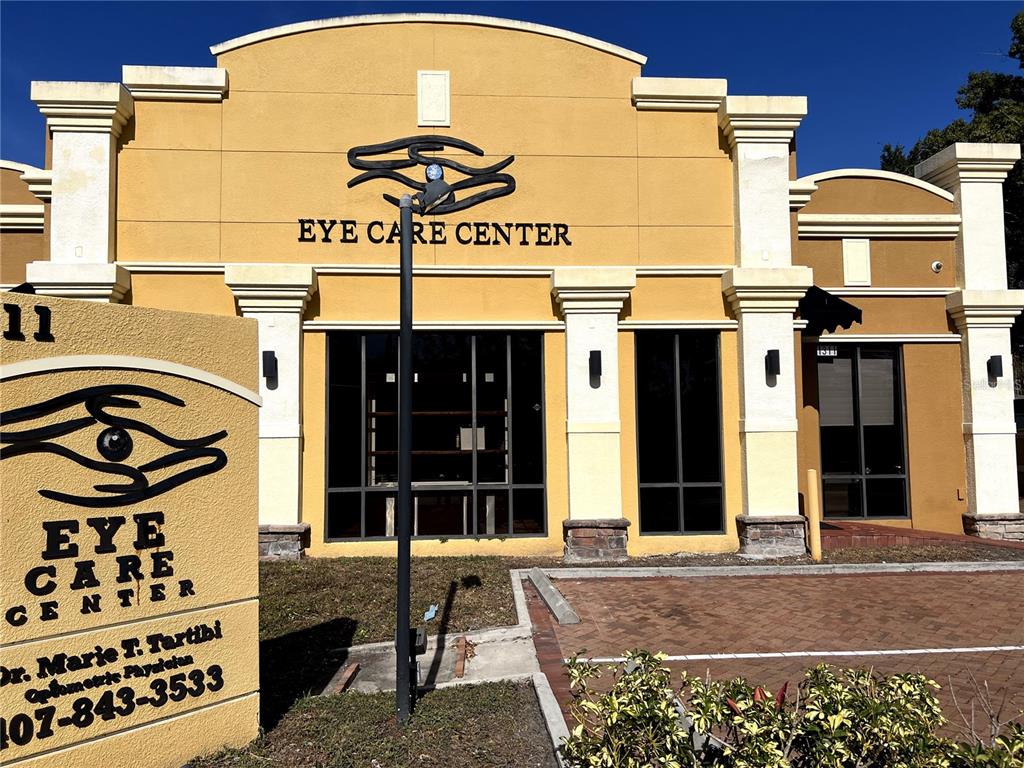 The exterior of a yellow commercial building features an eye logo and signage for an eye care center — 1313 E MICHIGAN STREET, ORLANDO, FL