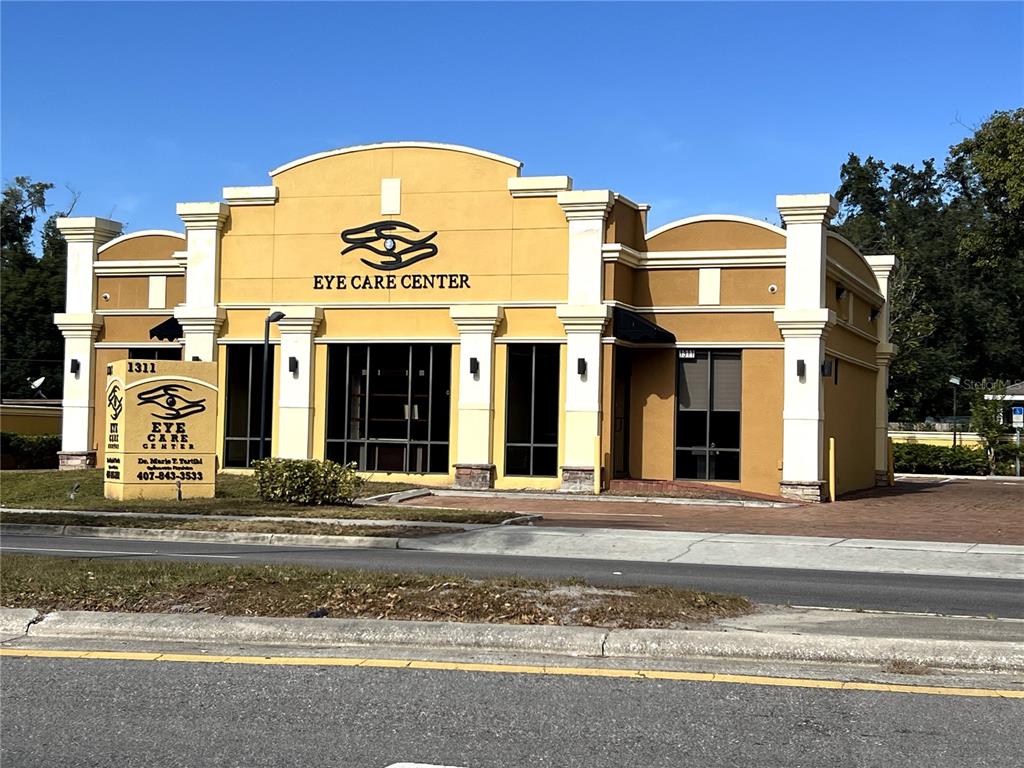 A yellow commercial building with a prominent eye logo and a matching freestanding sign — 1313 E MICHIGAN STREET, ORLANDO, FL
