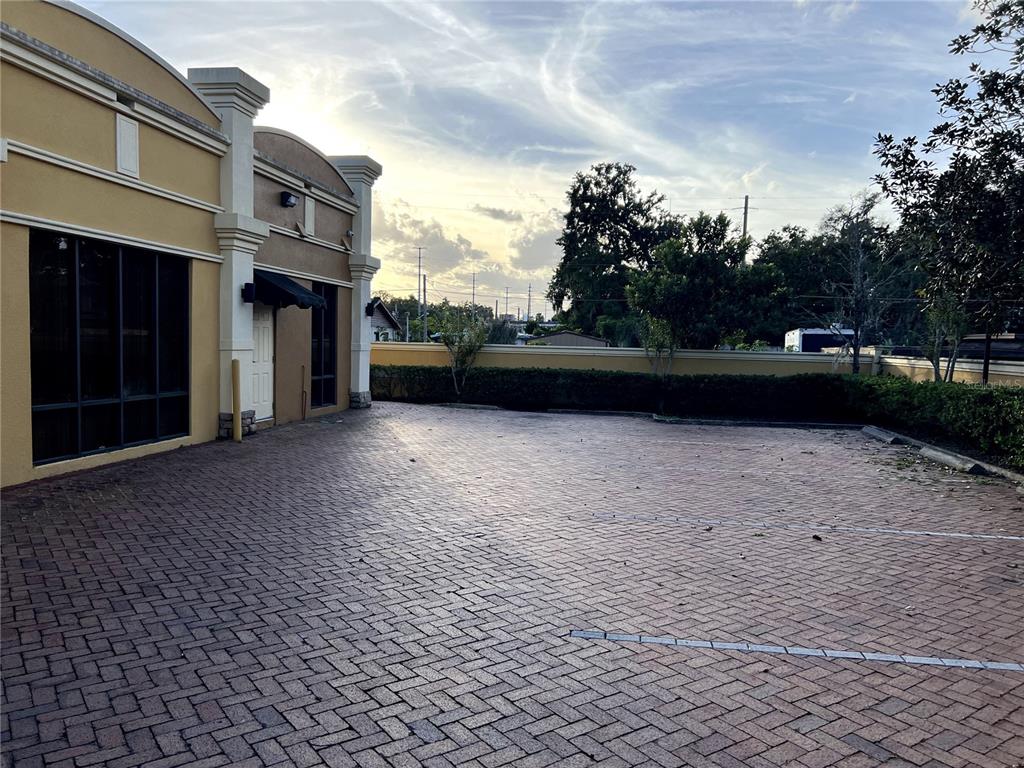 A paved parking area sits beside a tan commercial building with a brick-patterned surface — 1313 E MICHIGAN STREET, ORLANDO, FL